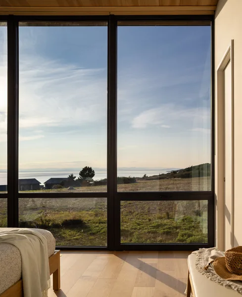 Room with floor-to-ceiling glazing providing a view of an exterior landscape and water.