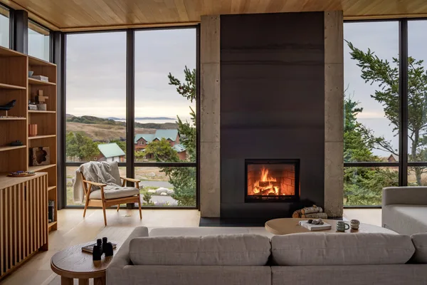 Living room with floor-to-ceiling glazing and a central fireplace flanked by concrete walls