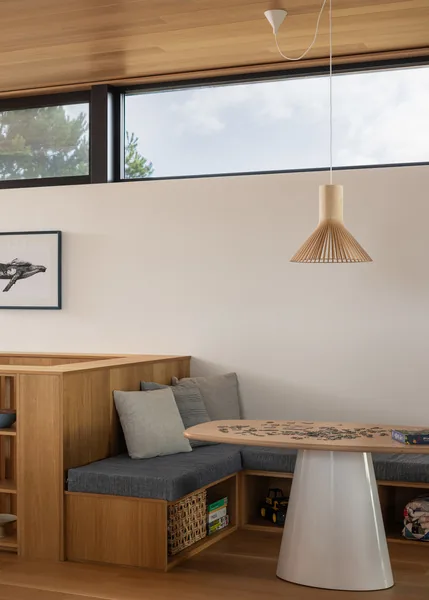 Dining nook with built-in wood bench seating and a wooden table beneath a pendant light and clerestory窗户.