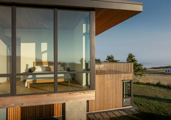 Modern bedroom with floor-to-ceiling glazing and wood siding on a cantilevered structure