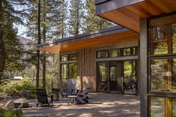 Outdoor patio at hillside house featuring wood ceiling, concrete flooring, and floor-to-ceiling glazing with metal frame.