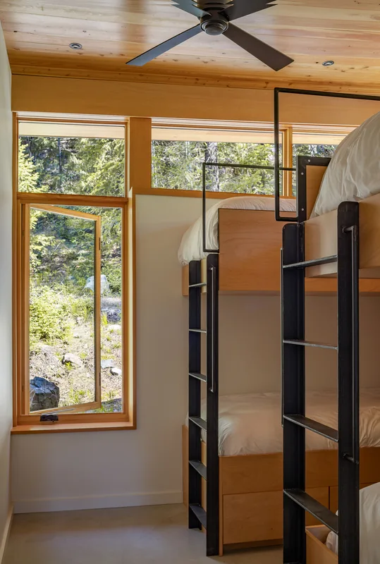 Bedroom with bunk beds and an open window looking out to greenery.