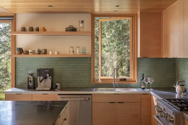 Kitchen featuring wood cabinets, green tiled backsplash, and stainless steel appliances.