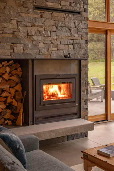 Modern stone fireplace with wood storage integrated to the side and sliding glass door to patio.
