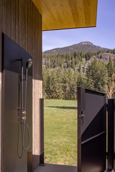 Outdoor shower and access gate with natural landscape view.