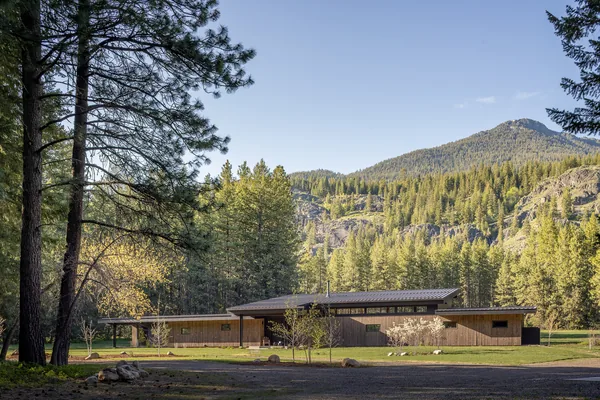 Exterior front view of a modern flat-roofed building with clerestory windows in a natural meadow landscape.