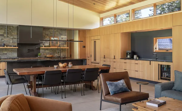 Modern kitchen and dining area featuring wood cabinetry, a large wooden dining table, and clerestory windows for natural light.