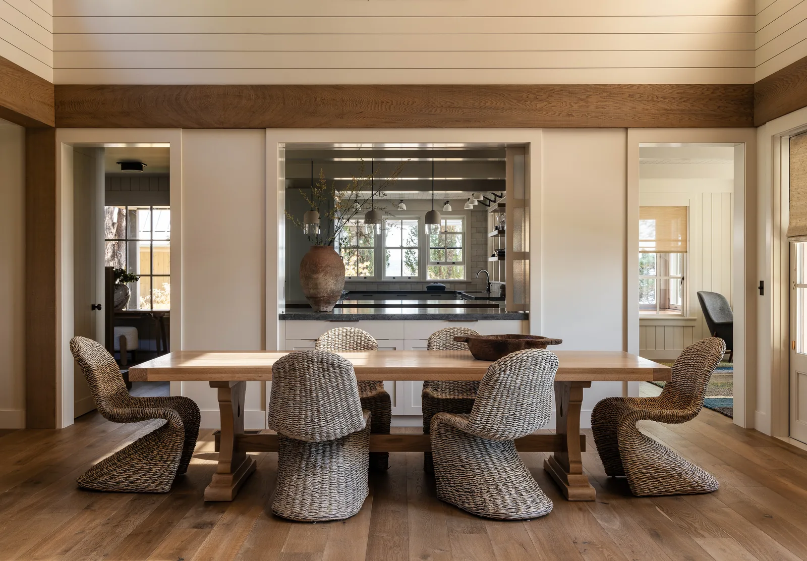 Dining room featuring a wooden table and wicker chairs with a pass-through window to the kitchen.
