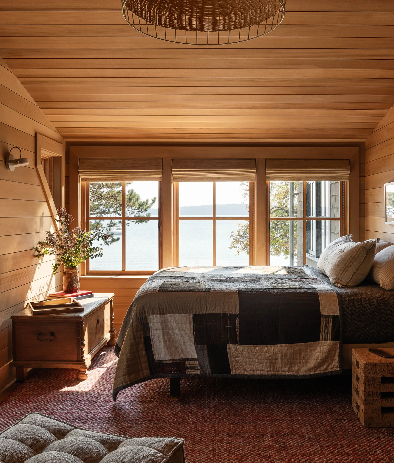 Wood-paneled bedroom featuring large grid windows providing water views.