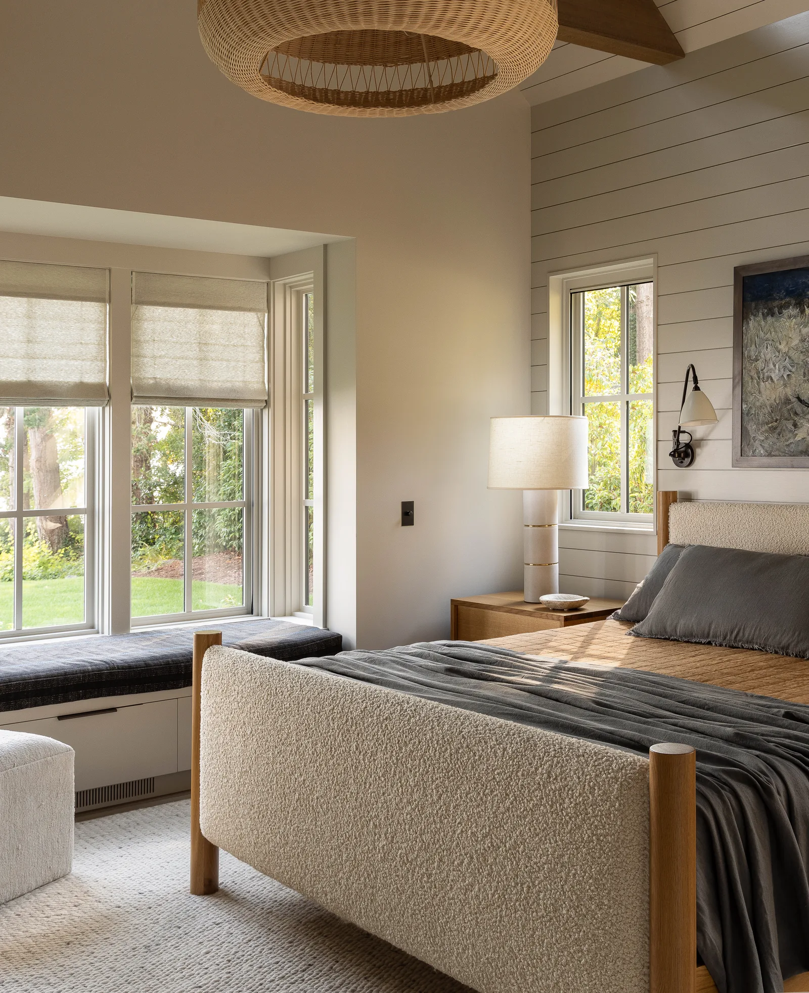 Bedroom featuring a cushioned bed, built-in window seat, and shiplap wall paneling with natural light from multiple windows.