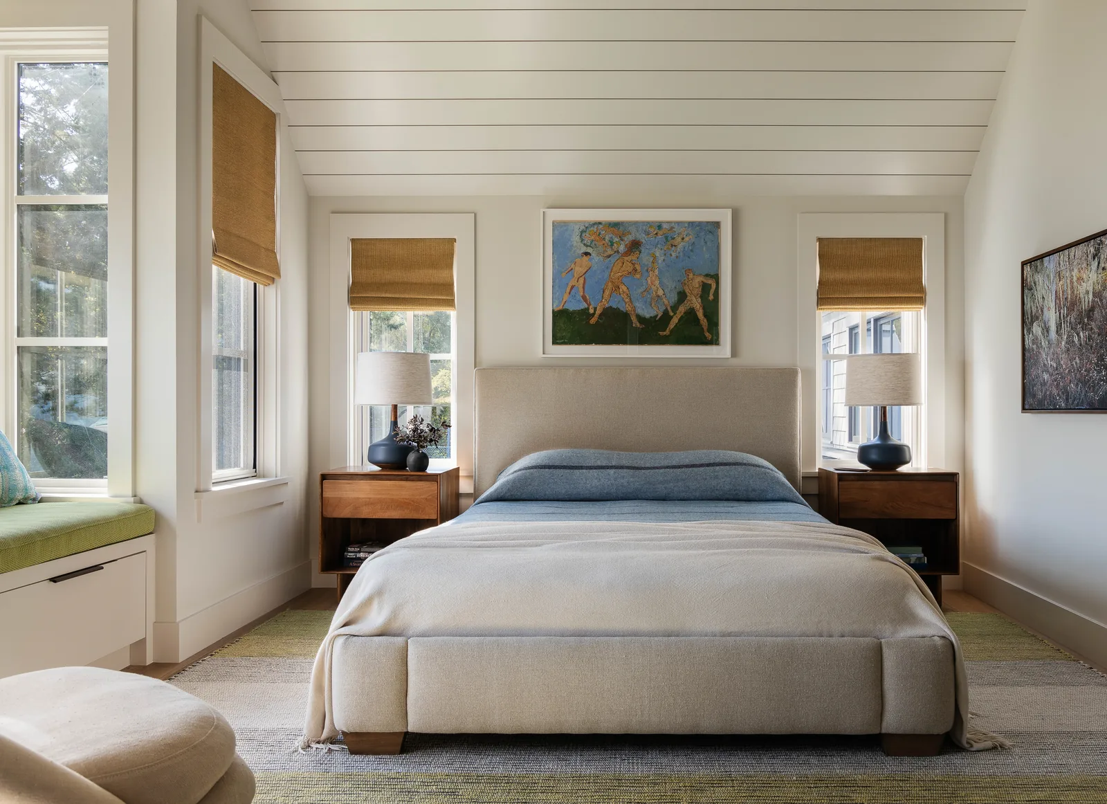 Bedroom features a vaulted ceiling, paired nightstands with lamps, and windows with woven shades.