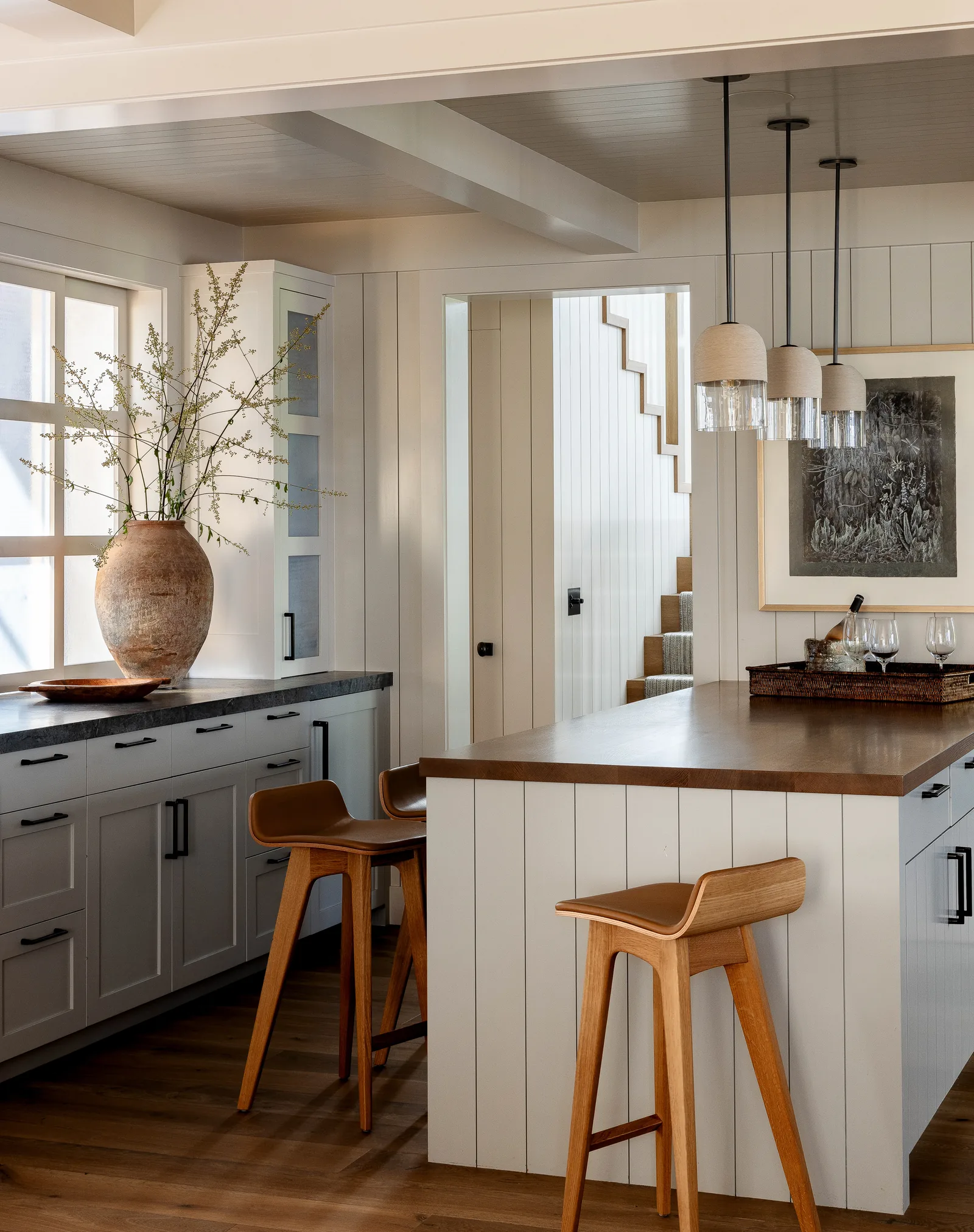 Kitchen featuring white cabinetry, wood flooring, wooden island, and pendant lights above seating area.