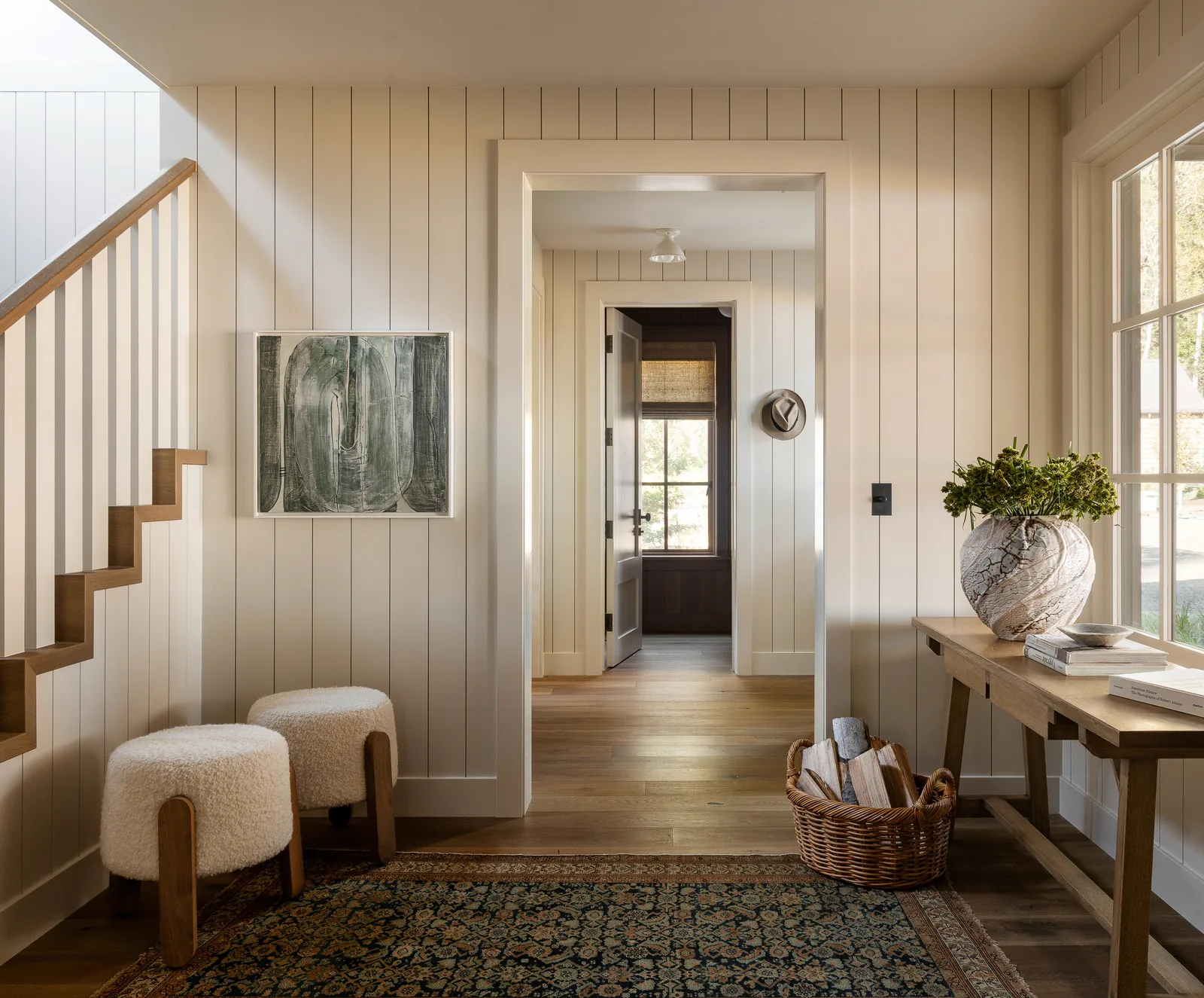 Entryway with wood staircase and furniture showing vertical wall paneling and wood flooring.