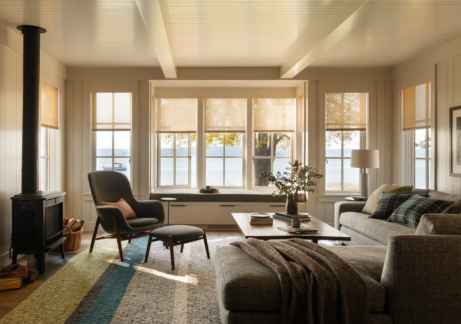 Living room with large waterfront windows, a wood-burning stove, and contemporary furniture.
