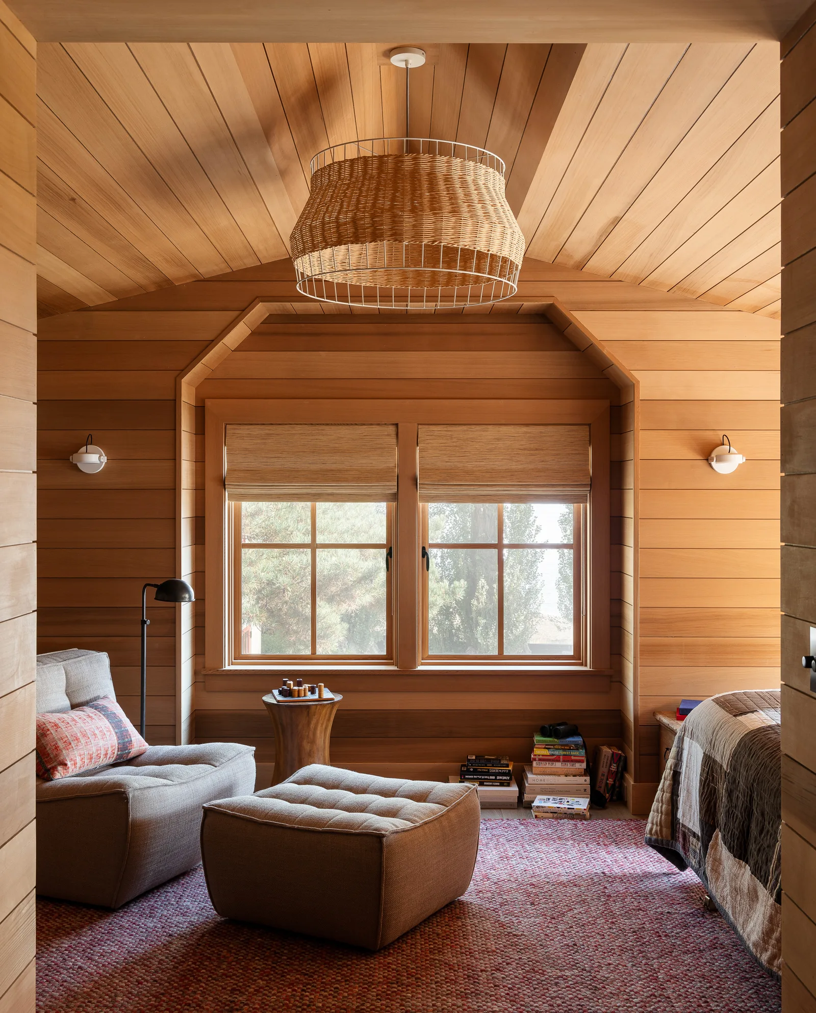 Interior view of a wood-paneled room with a large window, lounge chair, and ottoman.
