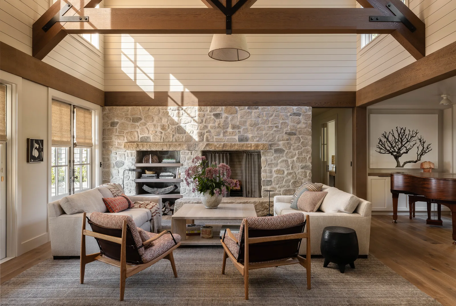 Living room with vaulted ceiling, exposed wood beams, and a stone fireplace in South Beach project.