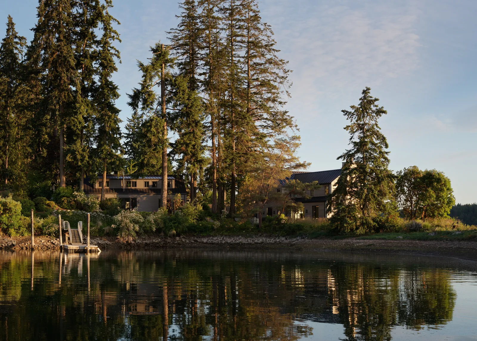 Arrow Bay house situated on waterfront lot surrounded by mature trees with metal roofing visible.