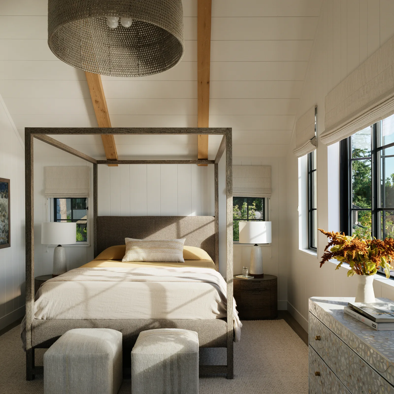 Bedroom features a four-poster bed under a vaulted ceiling with exposed wooden beams and three black-framed windows.