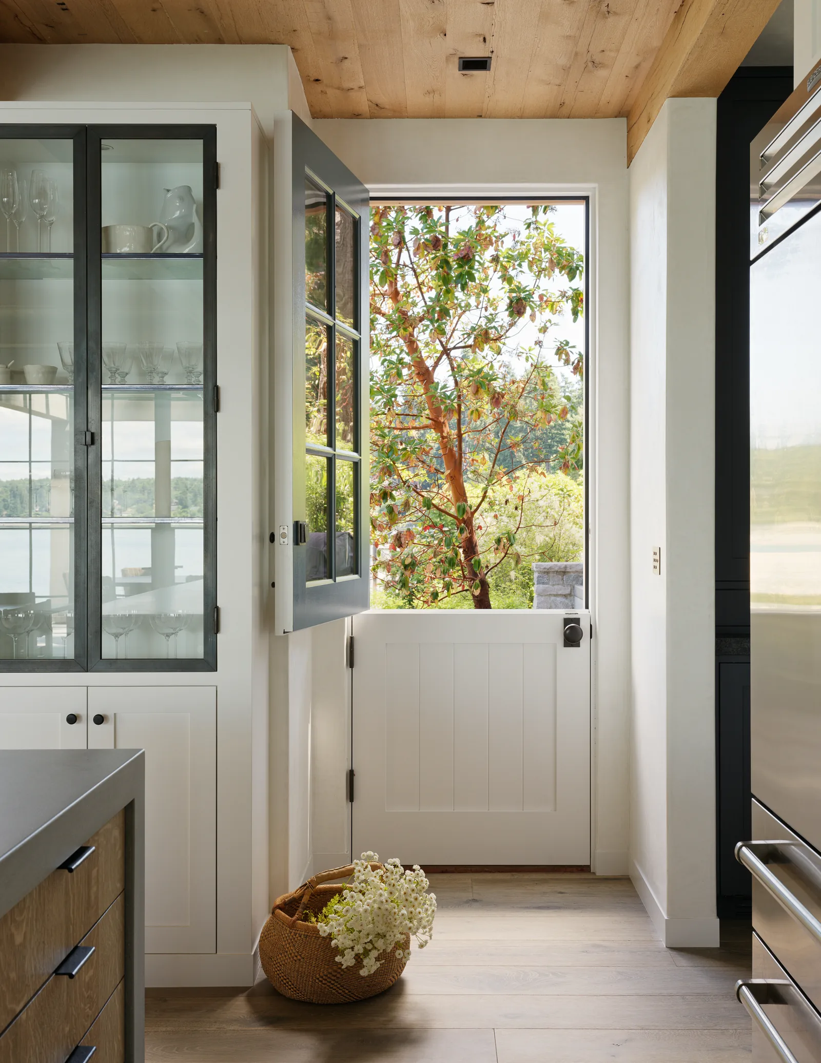 Dutch door in kitchen with glass cabinet and wood ceiling details.