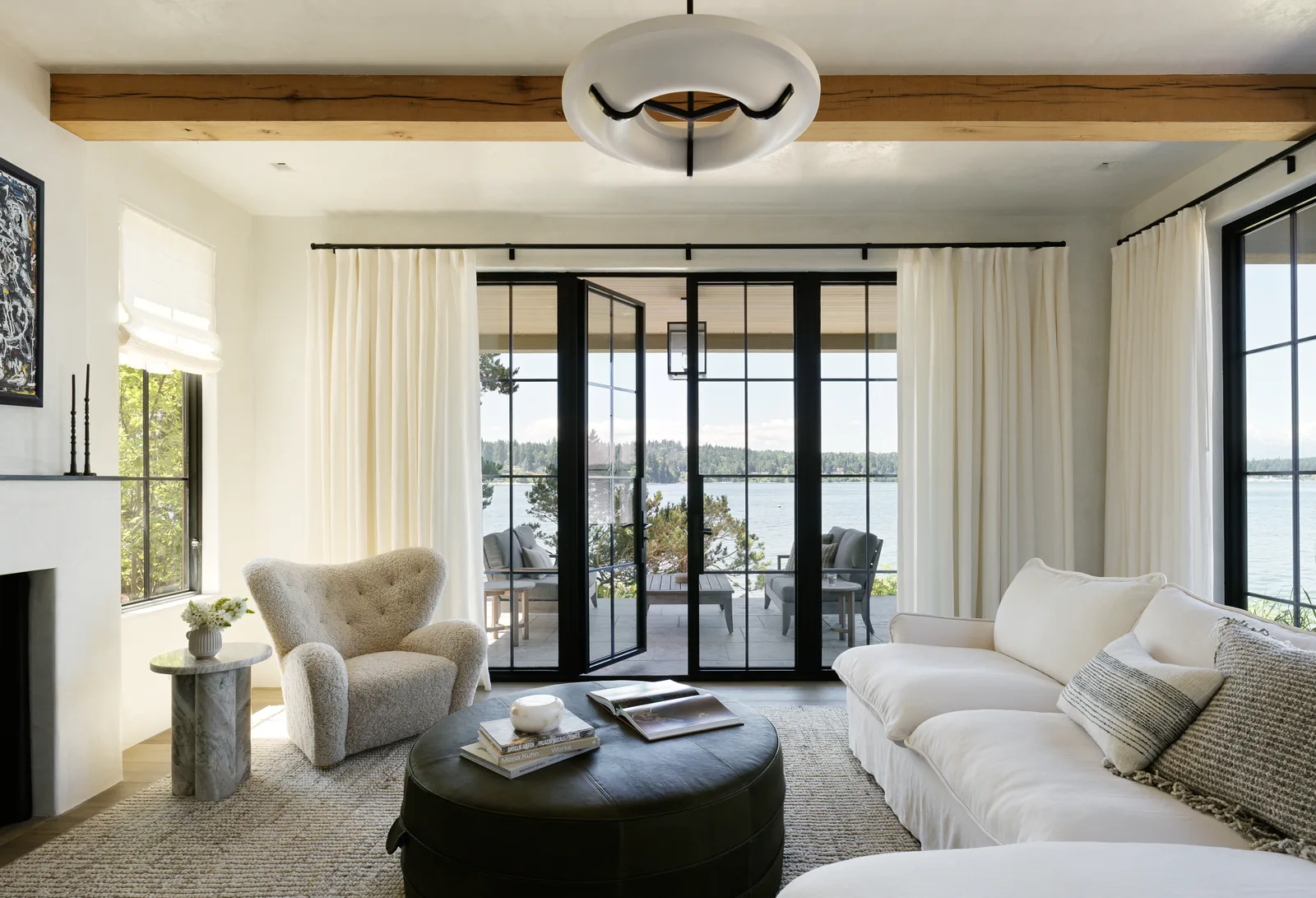 Living room featuring folding glass doors that open to an outdoor patio overlooking water.