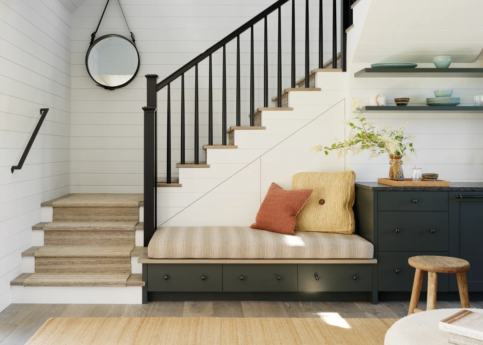 Staircase adjacent to built-in seating area and cabinetry with open shelving in a residential interior.