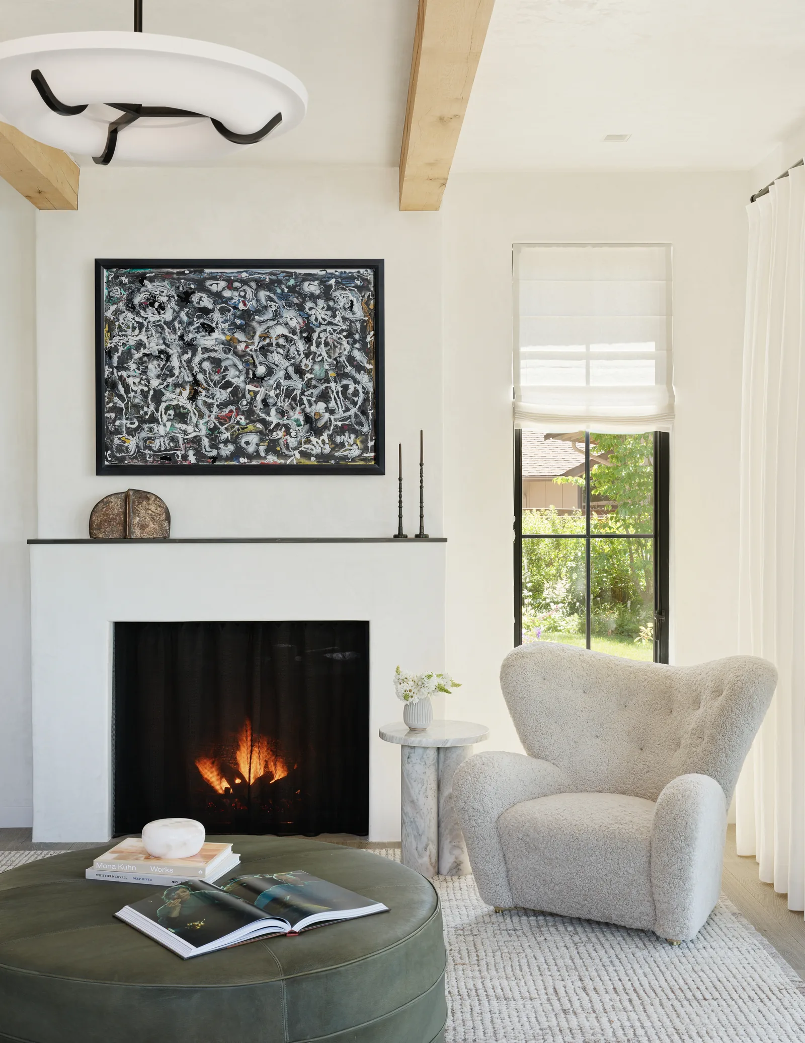 Living room with fireplace, textured armchair, and window with sheer roman shade.