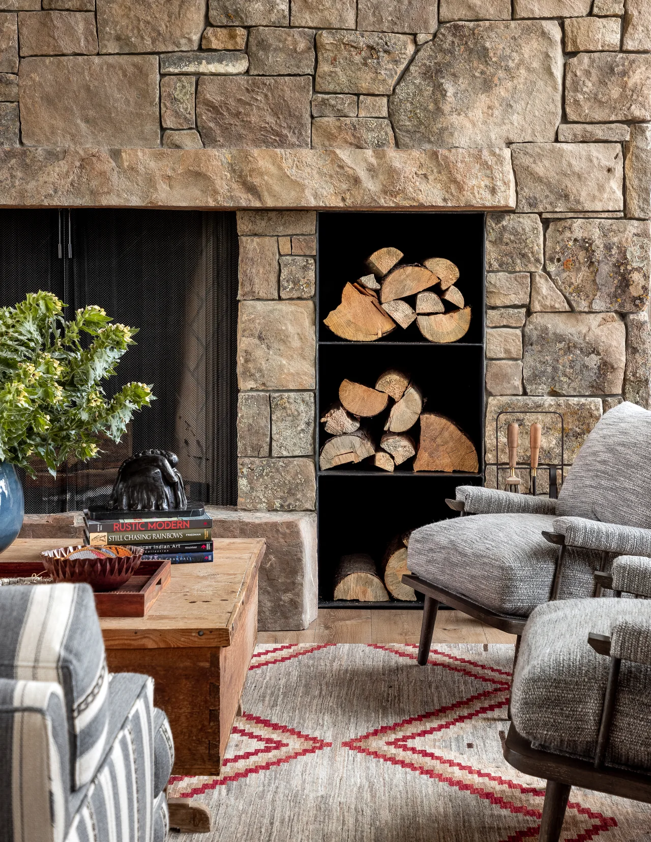 Stone fireplace with built-in shelves for firewood stacks in the Wyoming Retreat living room.