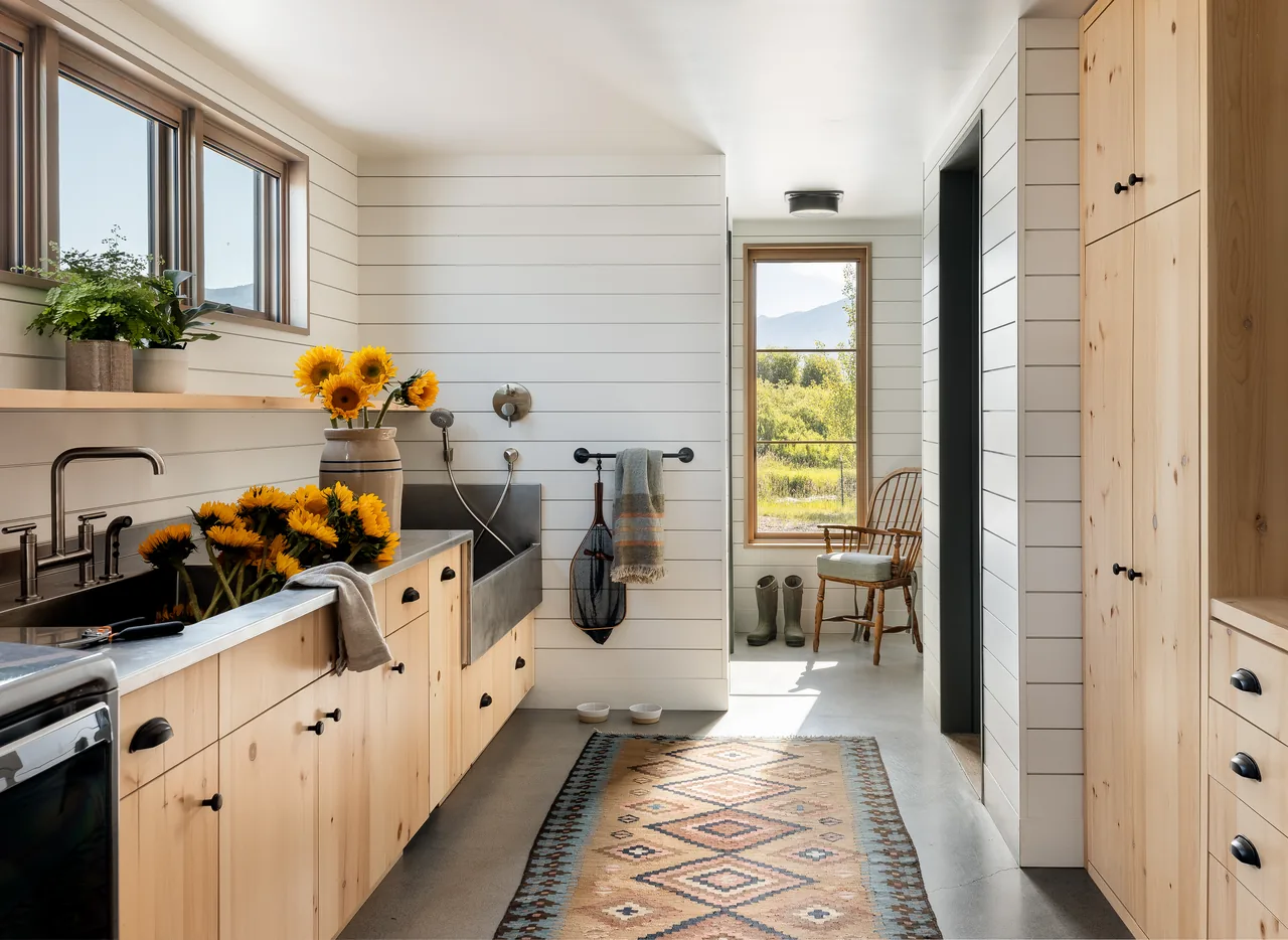 Laundry room features natural wood cabinets, a concrete farmhouse sink, and a clear window view of the outdoors.