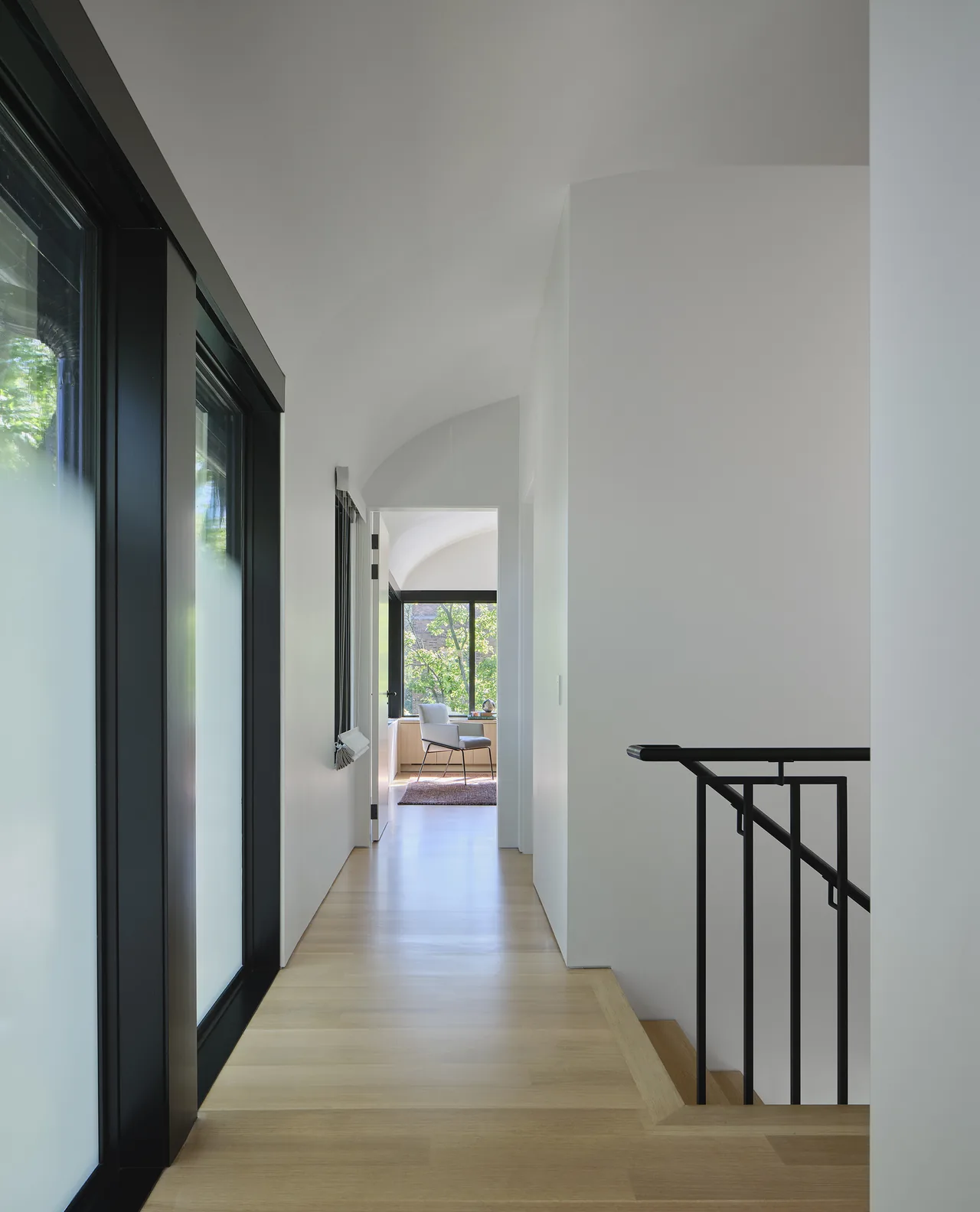 Hallway with curved ceiling and frosted glass windows looking toward a room with large windows at Lakewood Balmoral Residence.