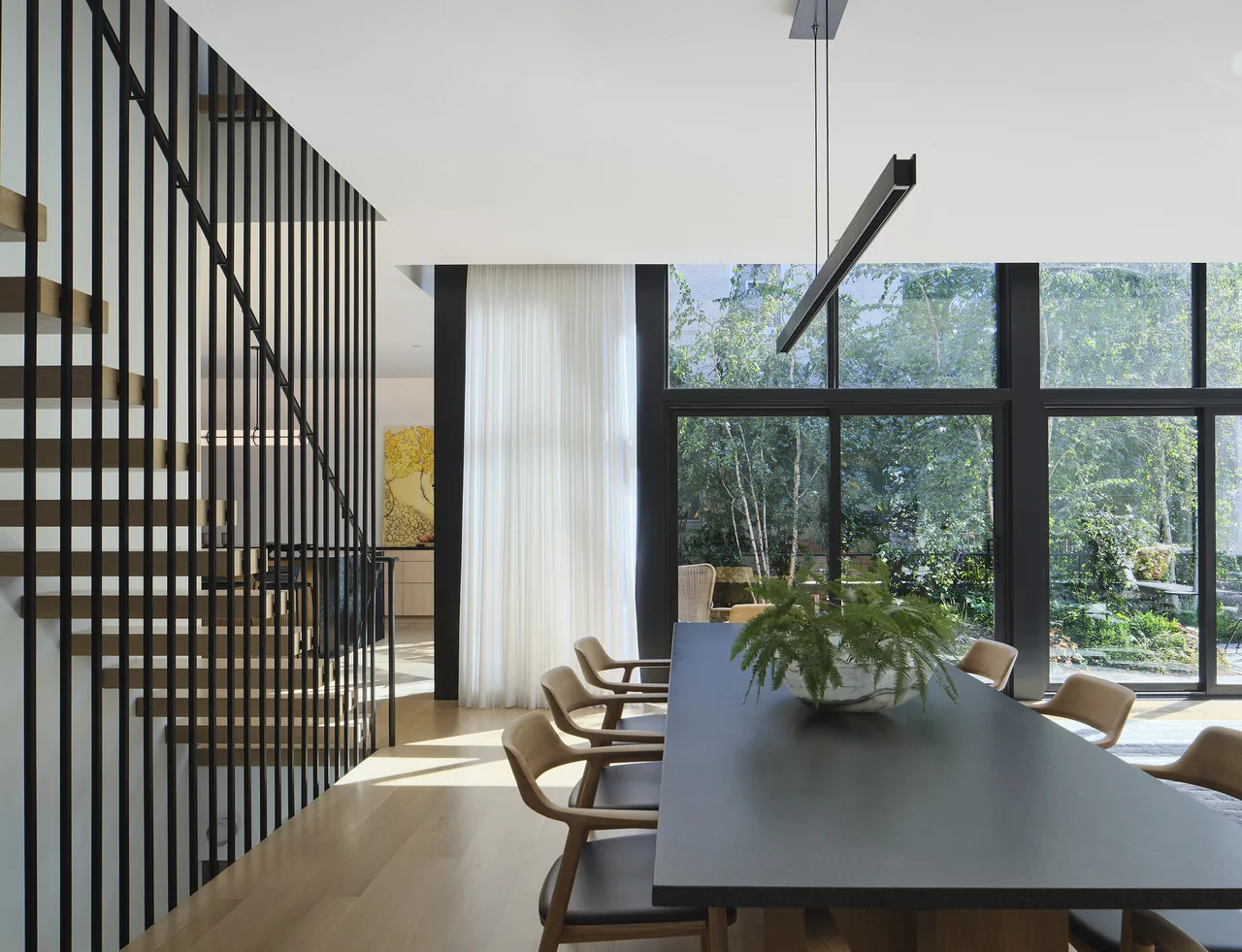 Dining room features a dark table, wooden chairs, floor-to-ceiling windows, and a linear pendant light.