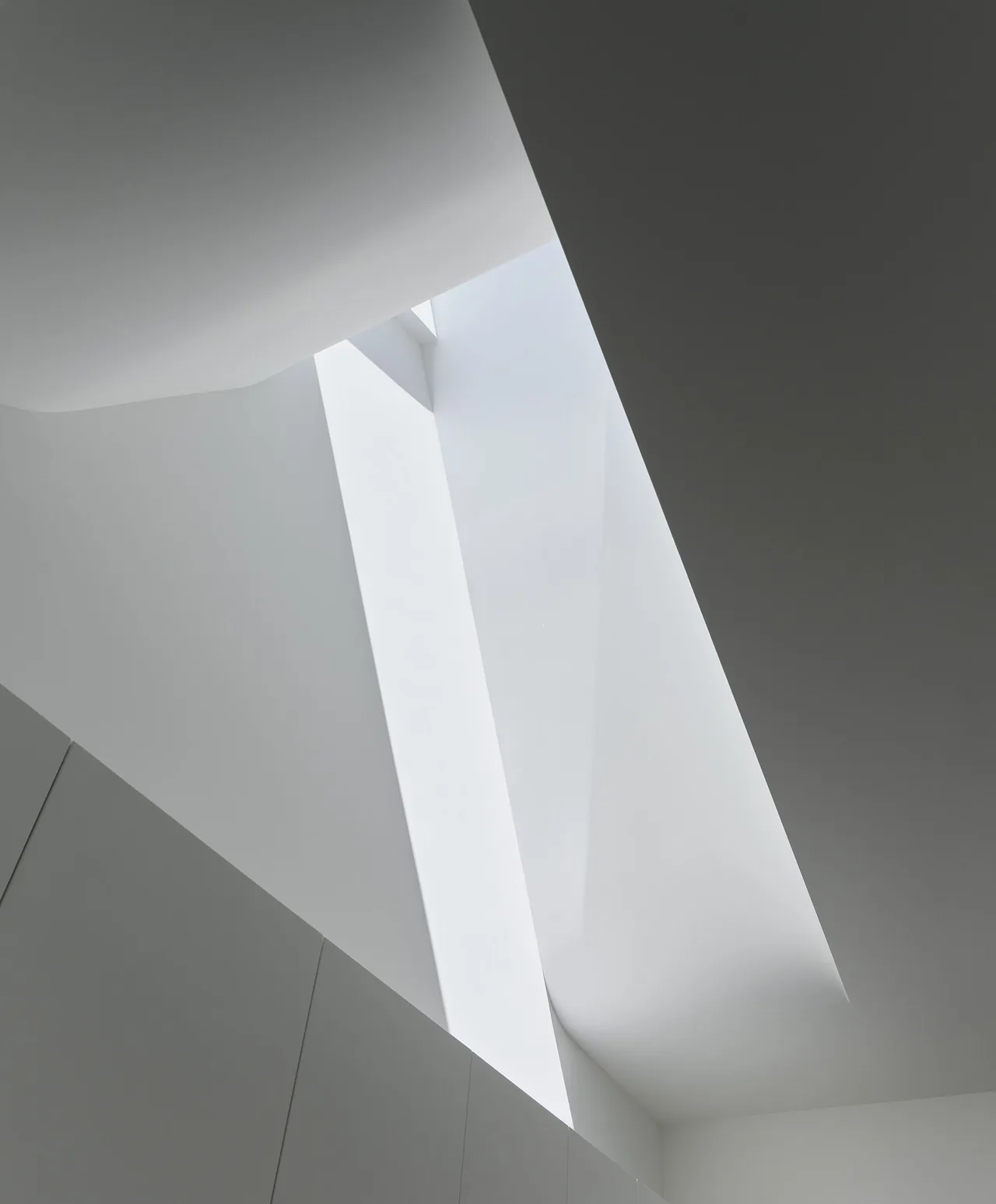 Long, narrow skylight with angular forms brings natural light into the white interior ceiling.