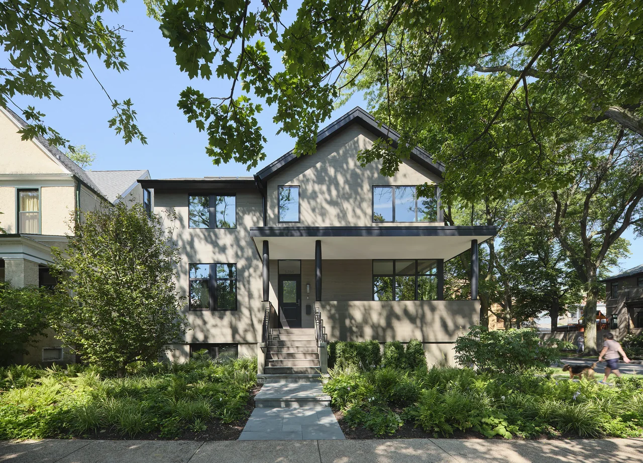 Front elevation of the Lakewood Balmoral Residence showing a two-story stucco house with large windows and a covered front porch.