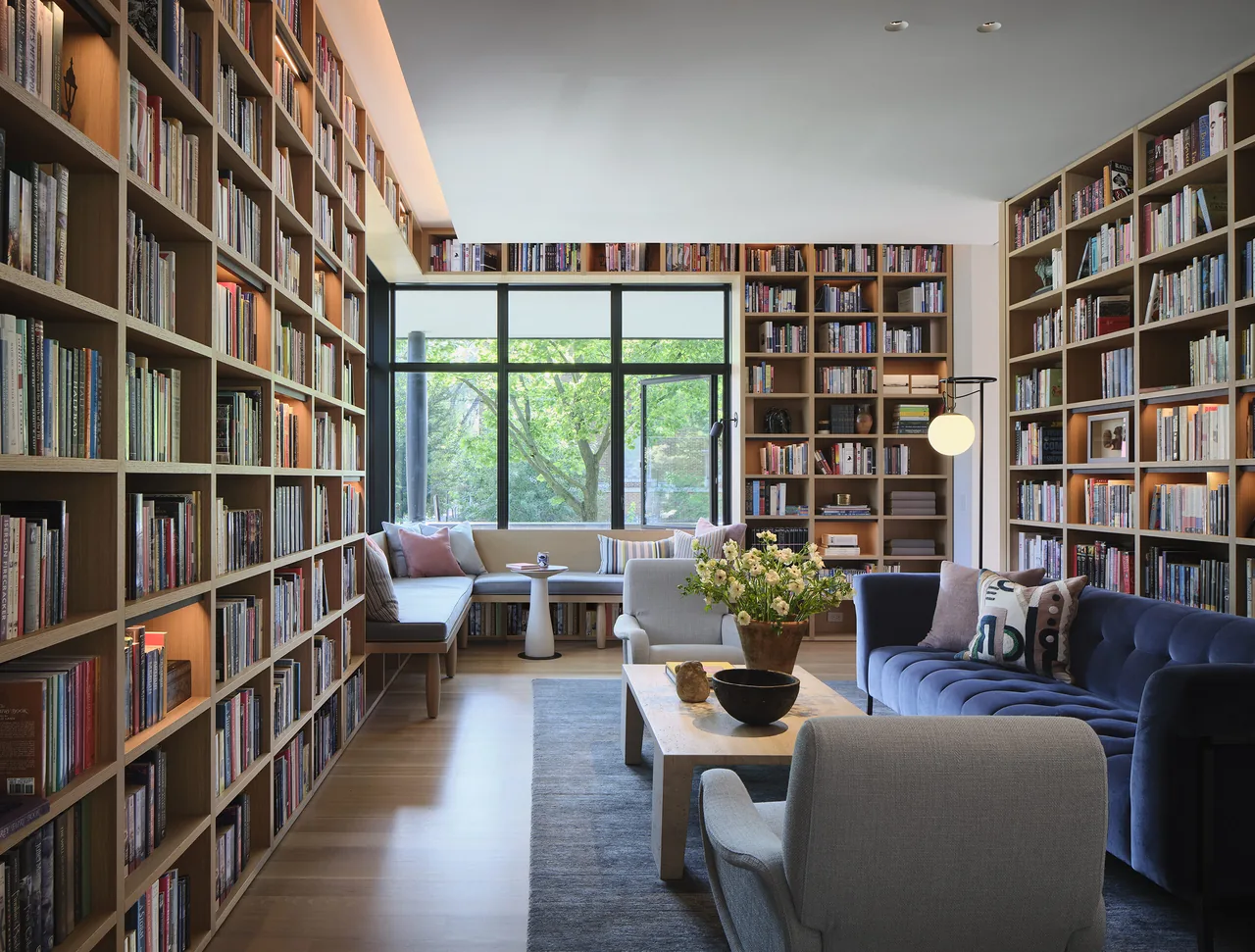 Living room of Lakewood Balmoral Residence features built-in bookshelves, a sectional sofa, and floor-to-ceiling glazing connecting indoors to outdoors.
