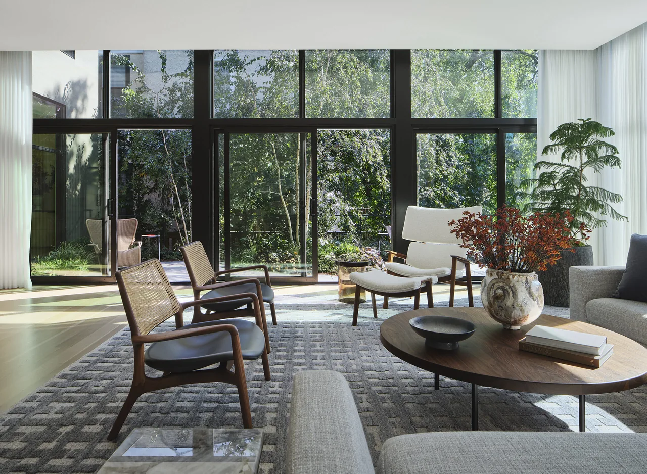 Living room features floor-to-ceiling sliding glass doors with black frames opening to a garden area.