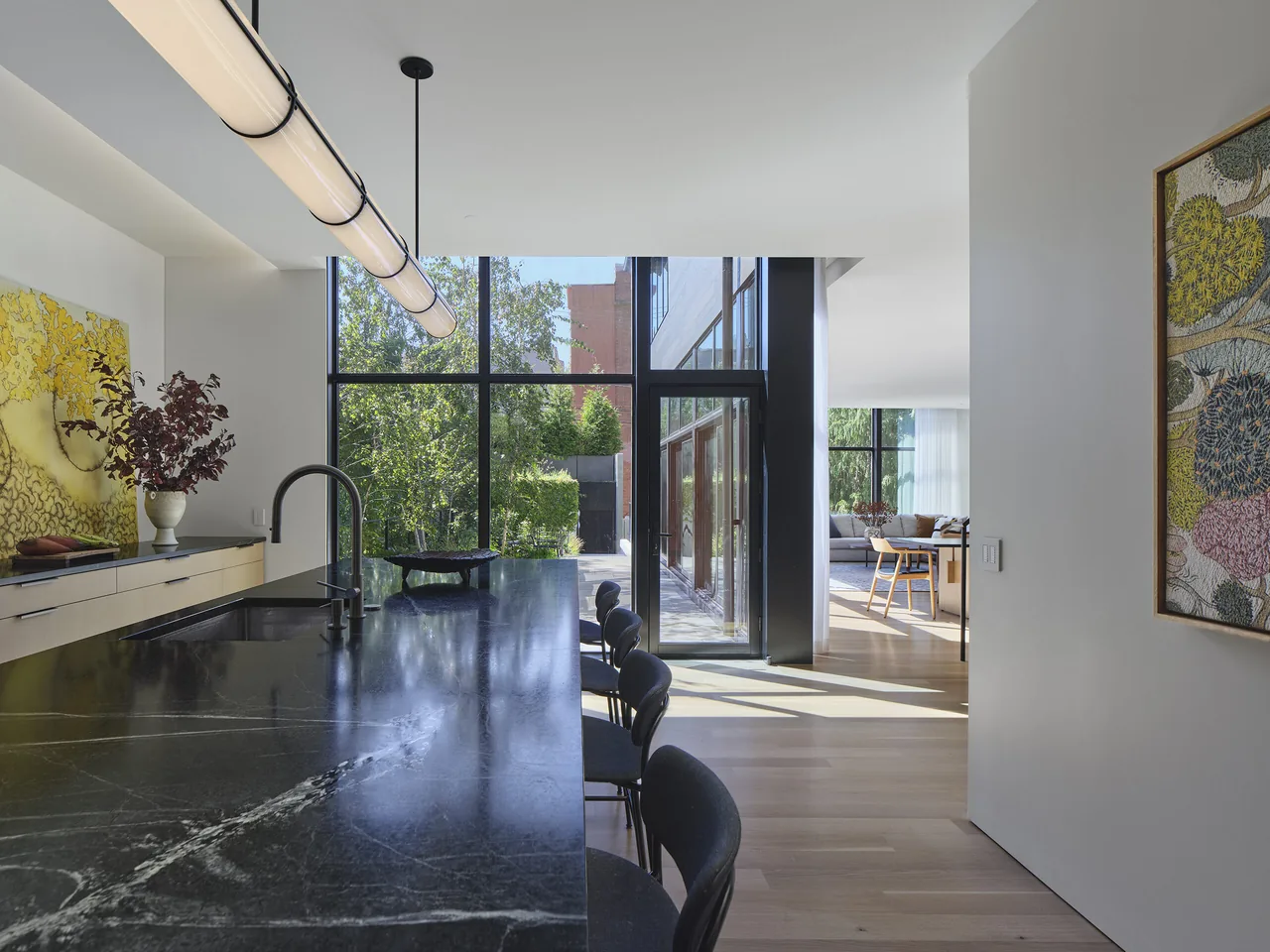 Kitchen area featuring a large black marble island and floor-to-ceiling glazing.