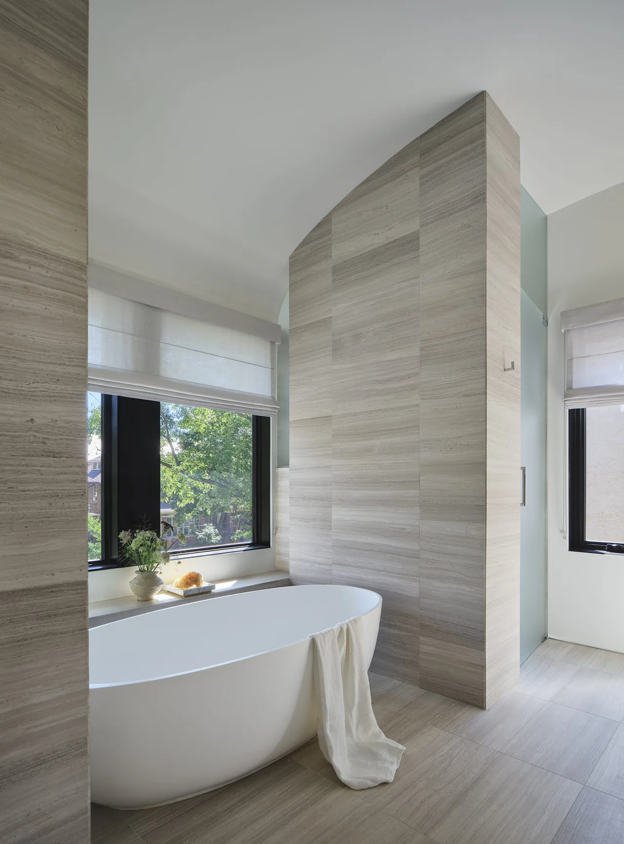 Bathroom featuring a freestanding tub and gray travertine tile surfaces at Lakewood Balmoral Residence.