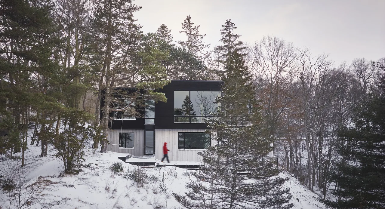 The Sawyer Retreat shows a two-story modern house with contrasting dark and light wood exterior in a winter forest setting.