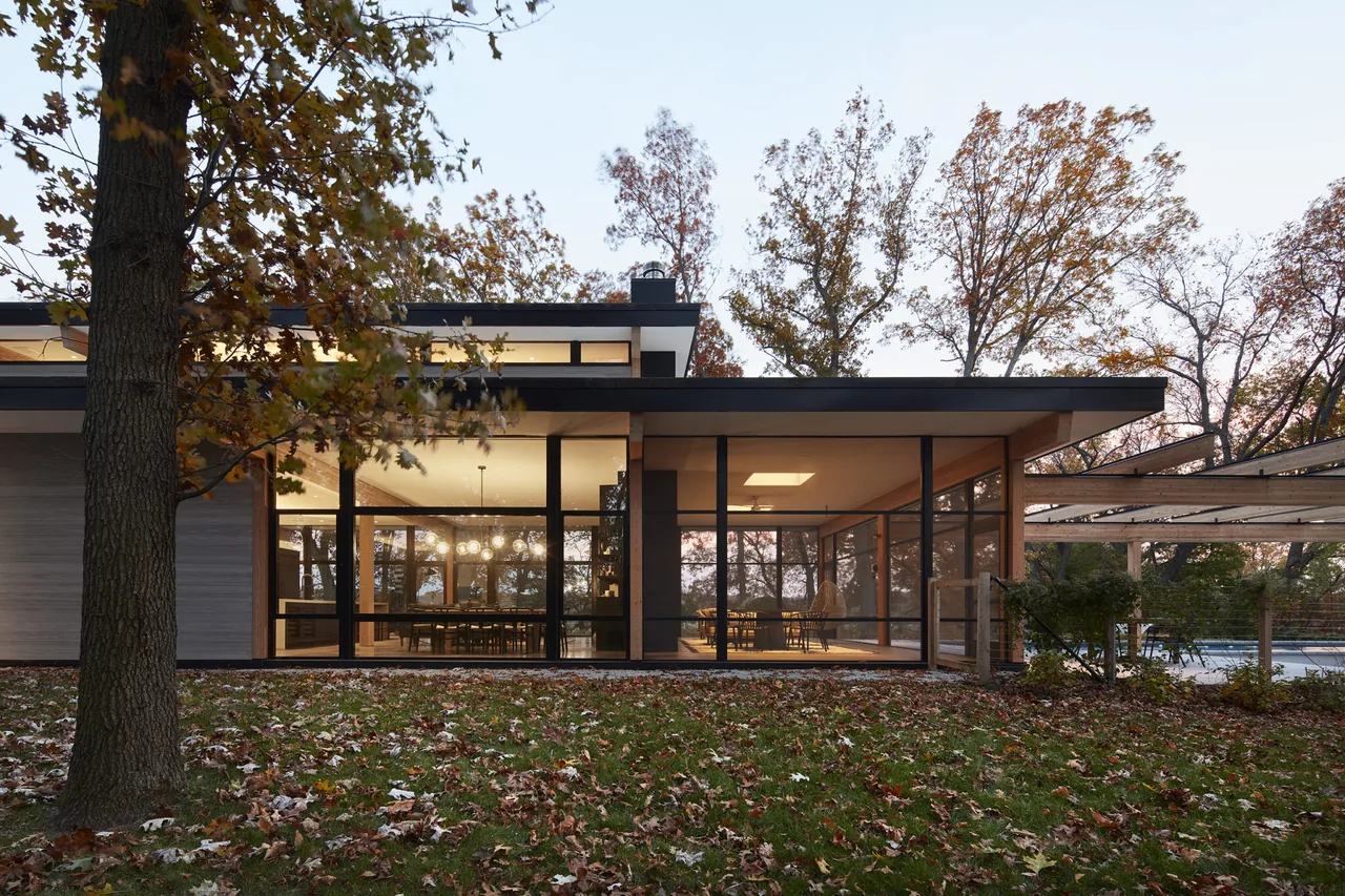 Exterior view of the Galien River Retreat showing extensive floor-to-ceiling glazing and a flat roof at dusk.