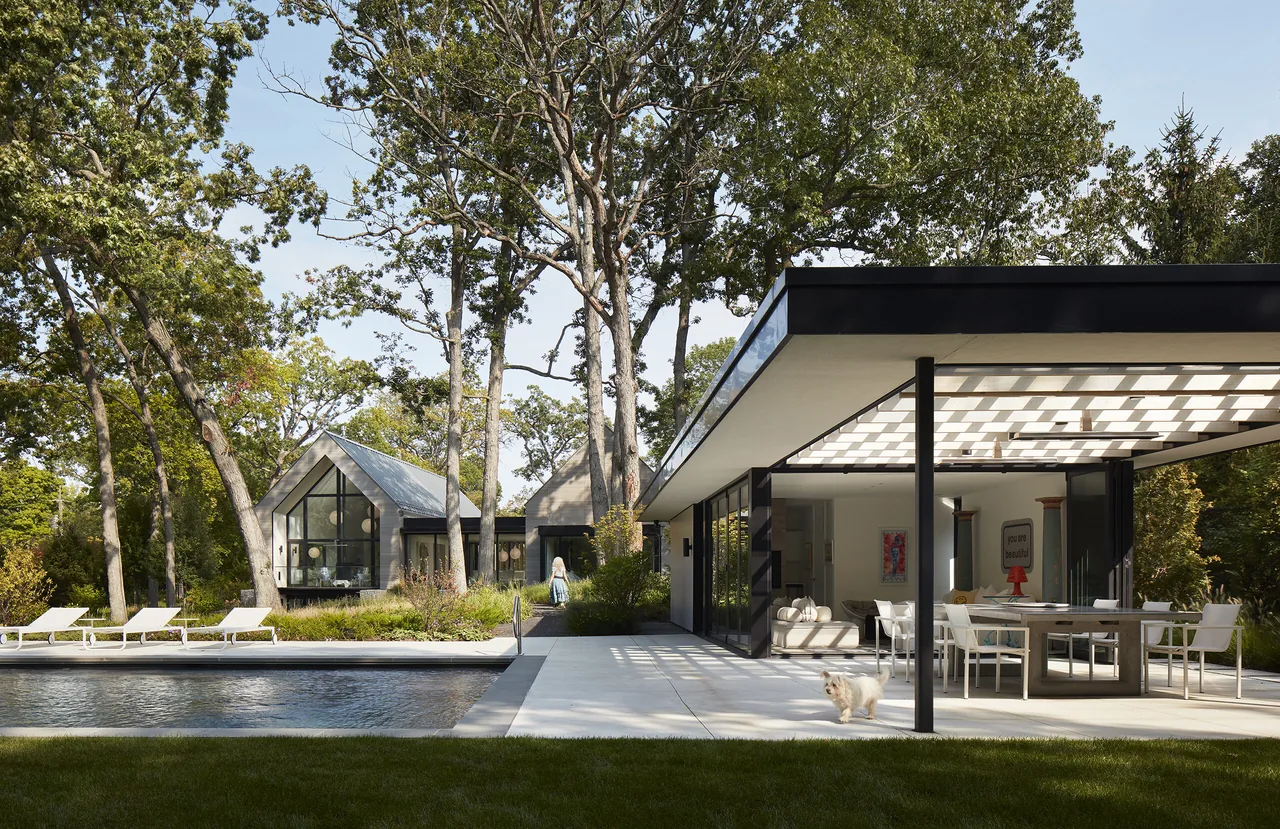 Exterior view of Two Gables project showing two gable-roofed buildings and a flat-roofed pavilion with outdoor pool and patio amenities.