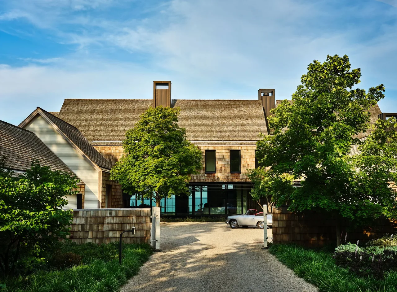 Exterior front view of a shingle-siding house with pitched roof and mature landscaping.