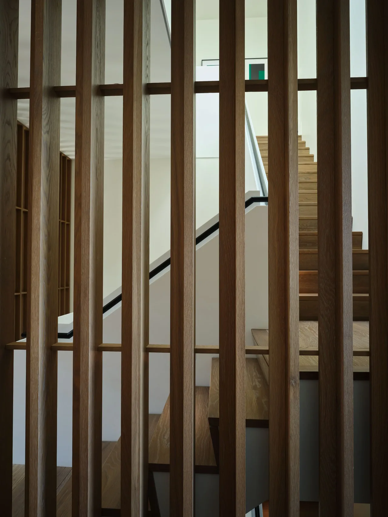 Modern interior staircase with vertical wood slats serving as a partial partition.