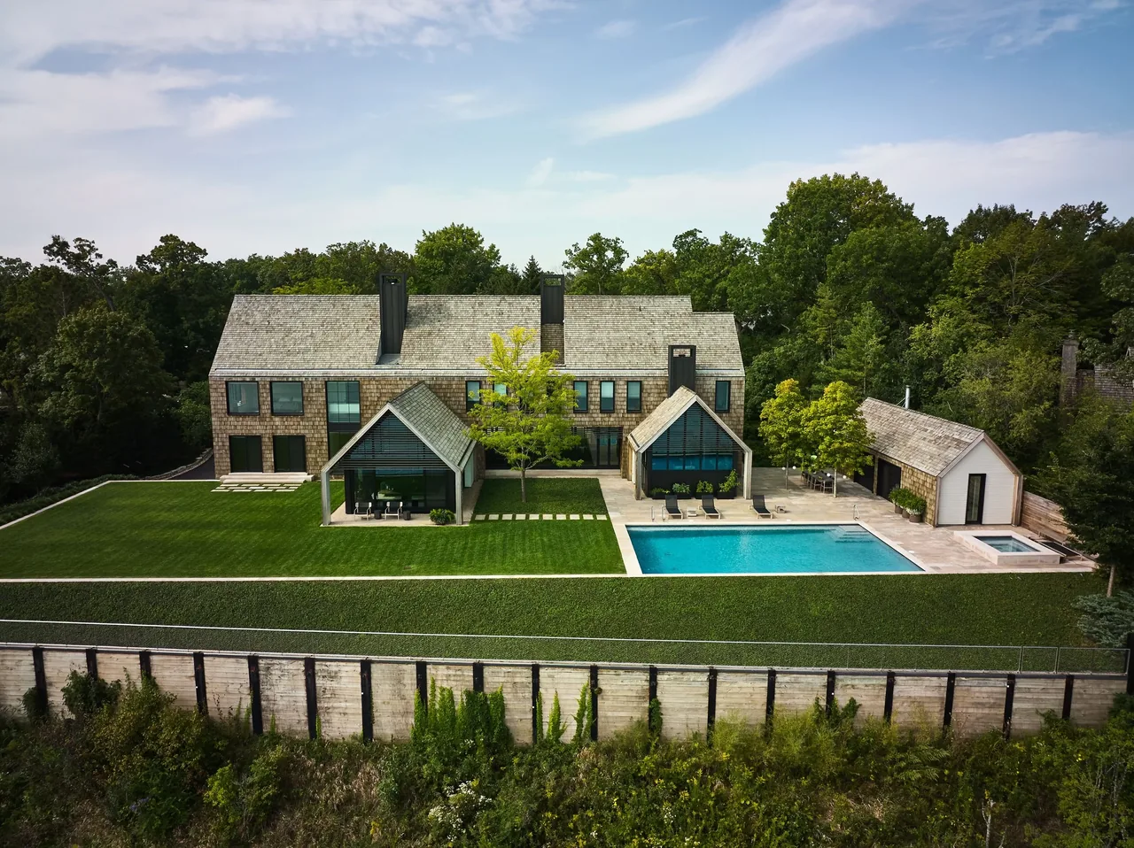 Blufftop house with shingle siding, multiple pitched roofs, pool, and patio.