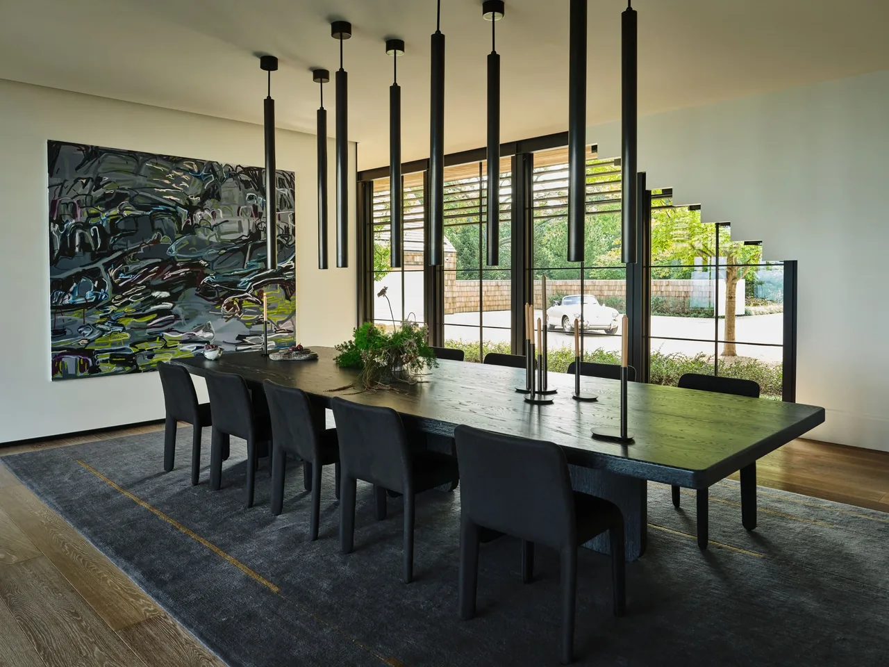 Interior view of a modern dining room with black furniture and a large window with a stair-shaped design detail.