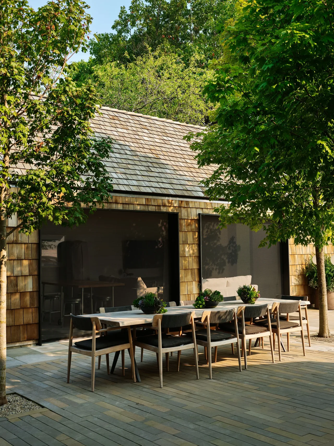 Outdoor patio dining area adjacent to a wood-shingled building with a sloped roof.