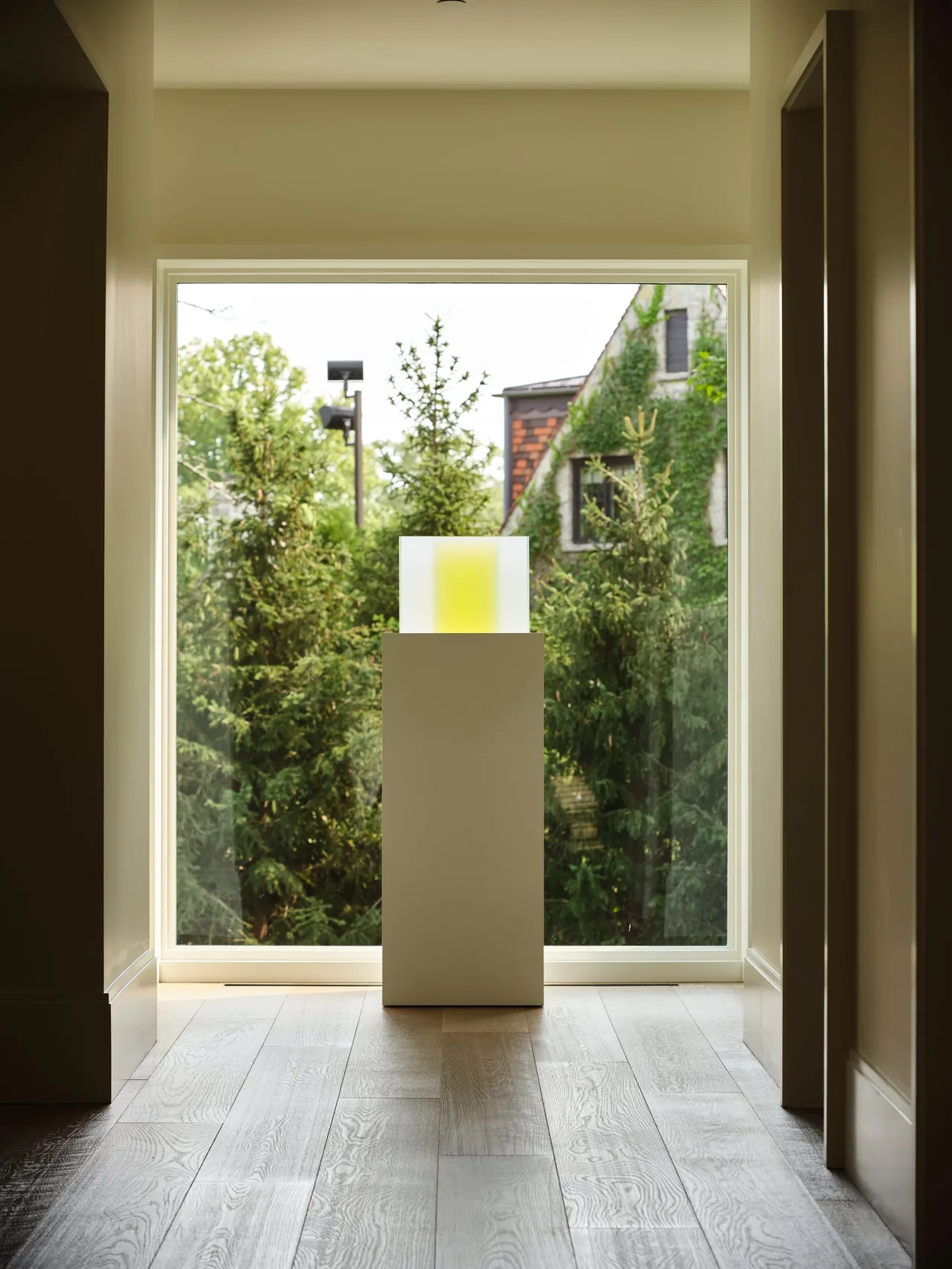 Hallway with large floor-to-ceiling window overlooking trees and a neighboring ivy-covered building