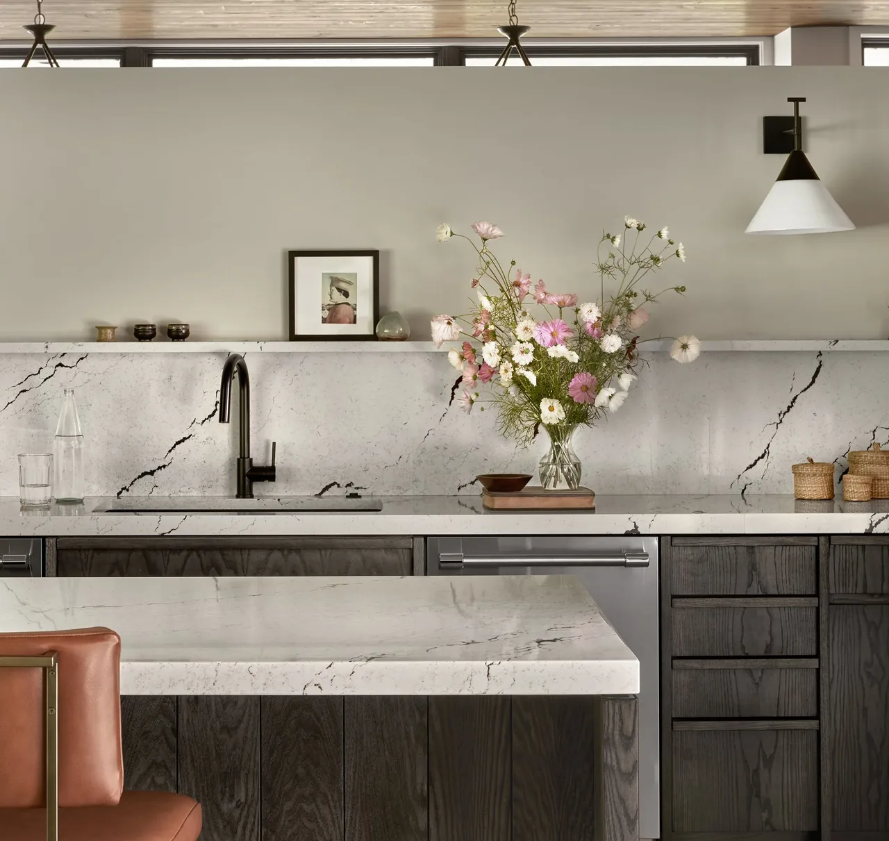 The kitchen features dark wood cabinets with white marble countertops and a black faucet over the sink.