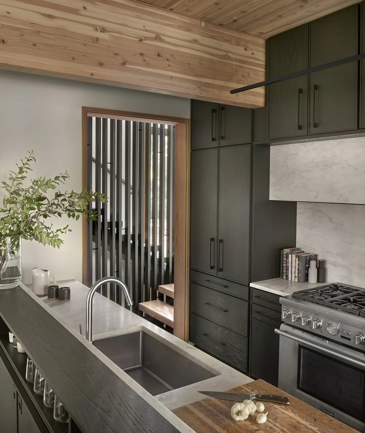 Kitchen with dark wood cabinets, stainless steel appliances, marble backsplash, and exposed wooden ceiling beam.