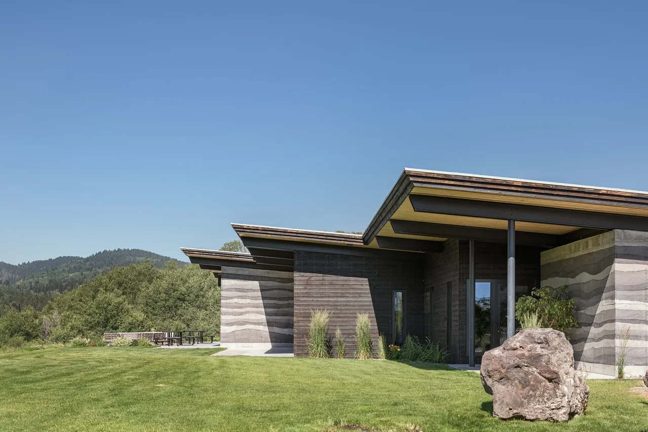 The Freedom Residence features a combination of rammed earth and wood walls with a flat roof and expansive overhangs.