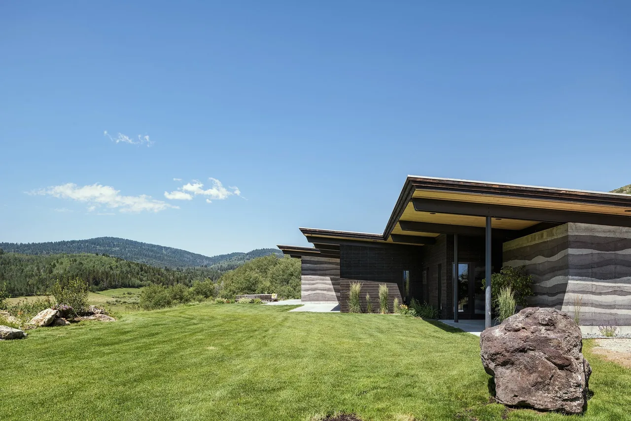 The Freedom Residence features horizontal rammed earth walls and expansive flat roofs in a natural rural setting.