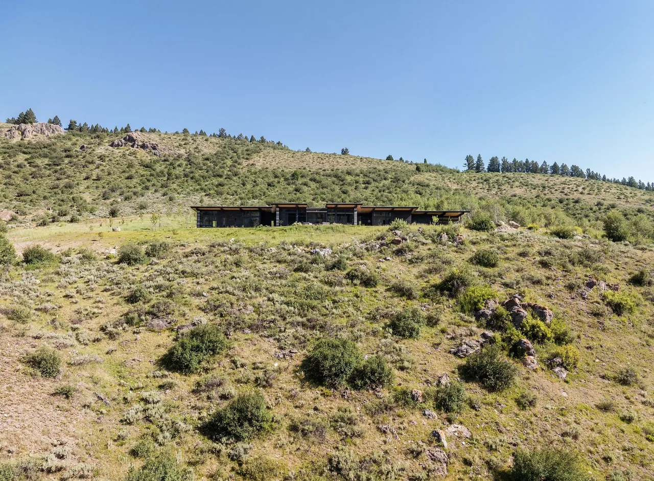 Exterior view of the Freedom Residence situated on a hillside with natural vegetation.